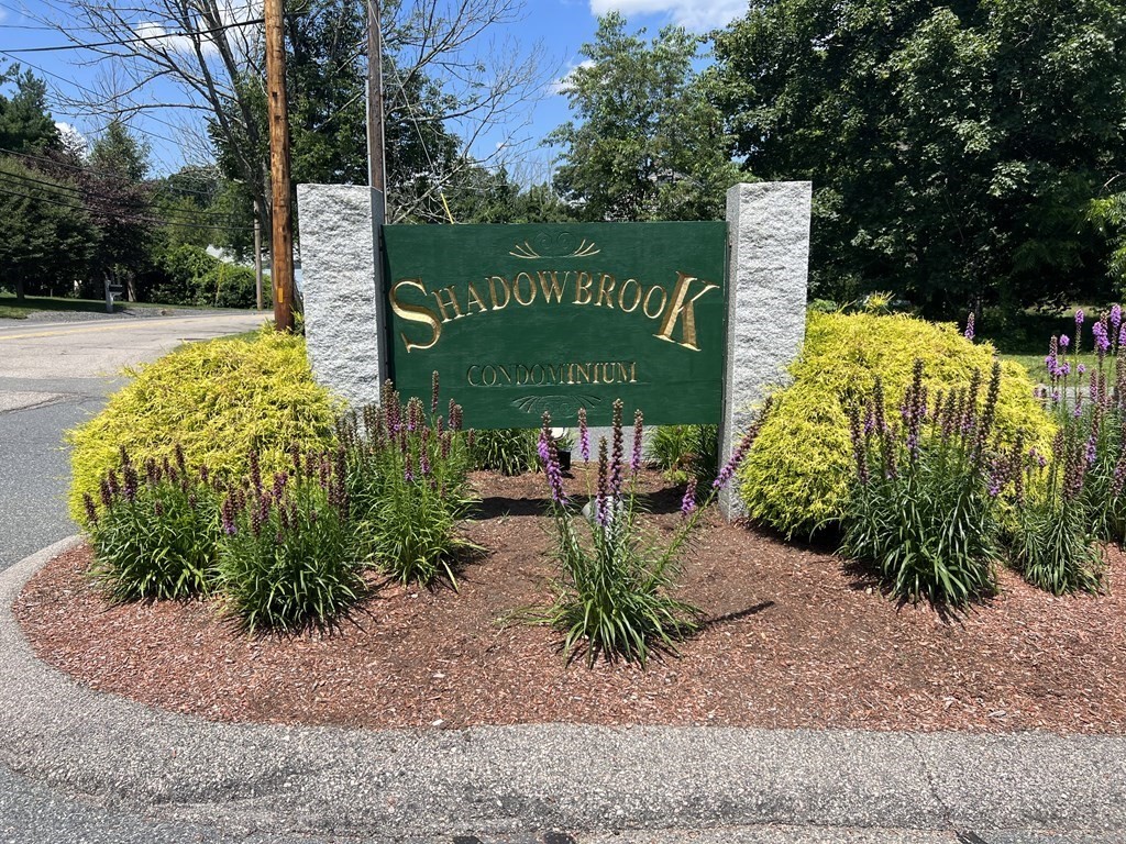 4 Shadowbrook Lane, Unit 6 Milford, MA 01757 - Photo 1 of 16 a sign that is sitting in front of flowers