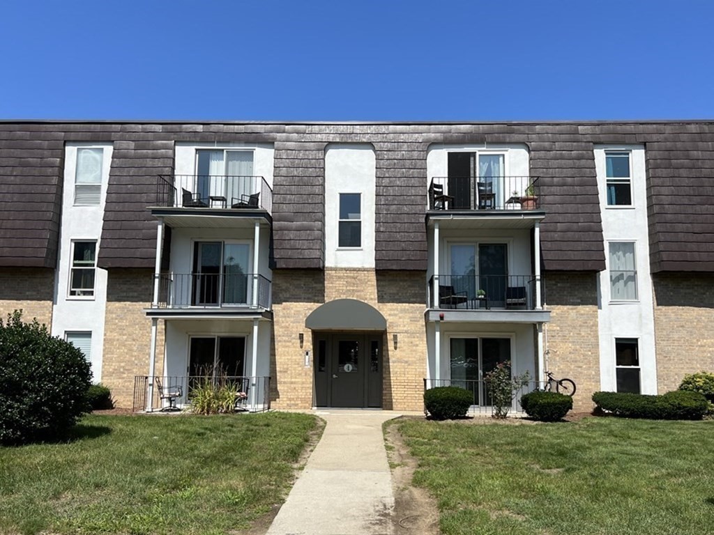4 Shadowbrook Lane, Unit 6 Milford, MA 01757 - Photo 2 of 16 a front view of a building with a garden