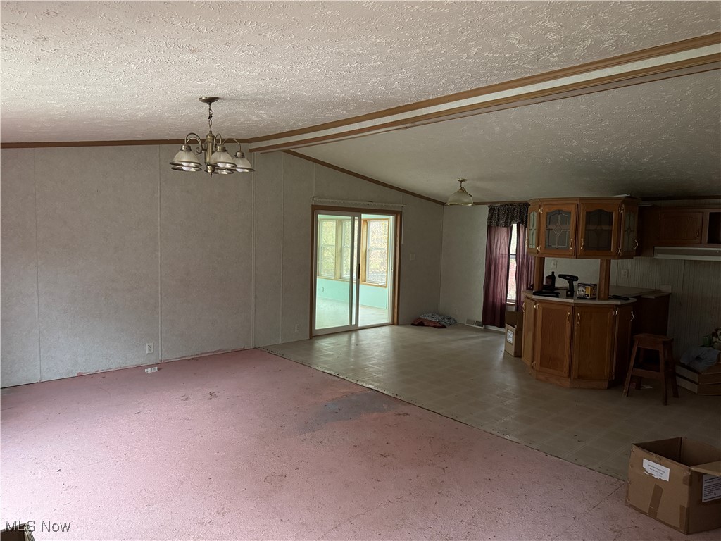 3690 Anderson Anthony Road Leavittsburg, OH 44430 - Photo 5 of 18 Unfurnished living room featuring vaulted ceiling, a chandelier, light flooring, a textured ceiling, and ornamental molding