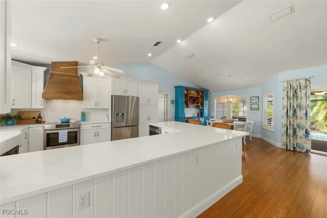 a large kitchen with stainless steel appliances a large counter top a stove and a refrigerator