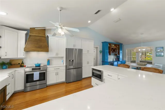 a kitchen with stainless steel appliances a stove a refrigerator a sink a oven with a dining table and chairs