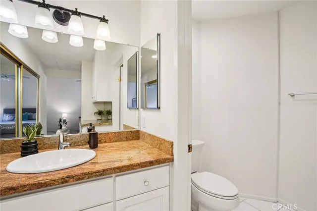 a bathroom with a granite countertop sink a toilet a mirror and shower
