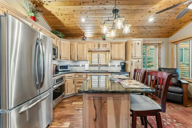 a kitchen with stainless steel appliances granite countertop a stove a refrigerator a sink dishwasher a dining table and chairs with wooden floor