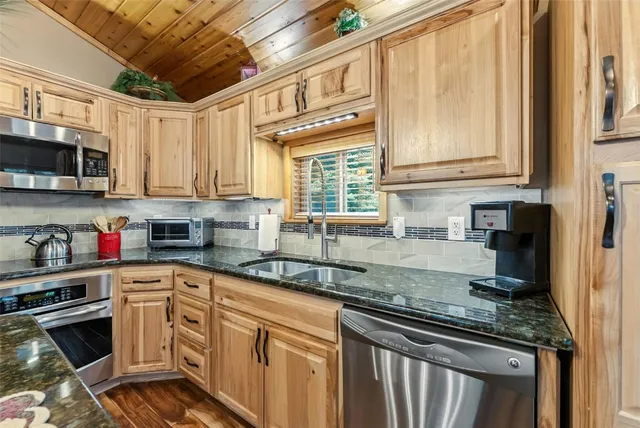 a kitchen with stainless steel appliances granite countertop a sink a stove and cabinets