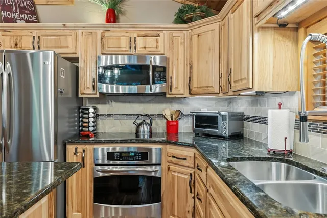 a kitchen with granite countertop a stove a sink and a refrigerator