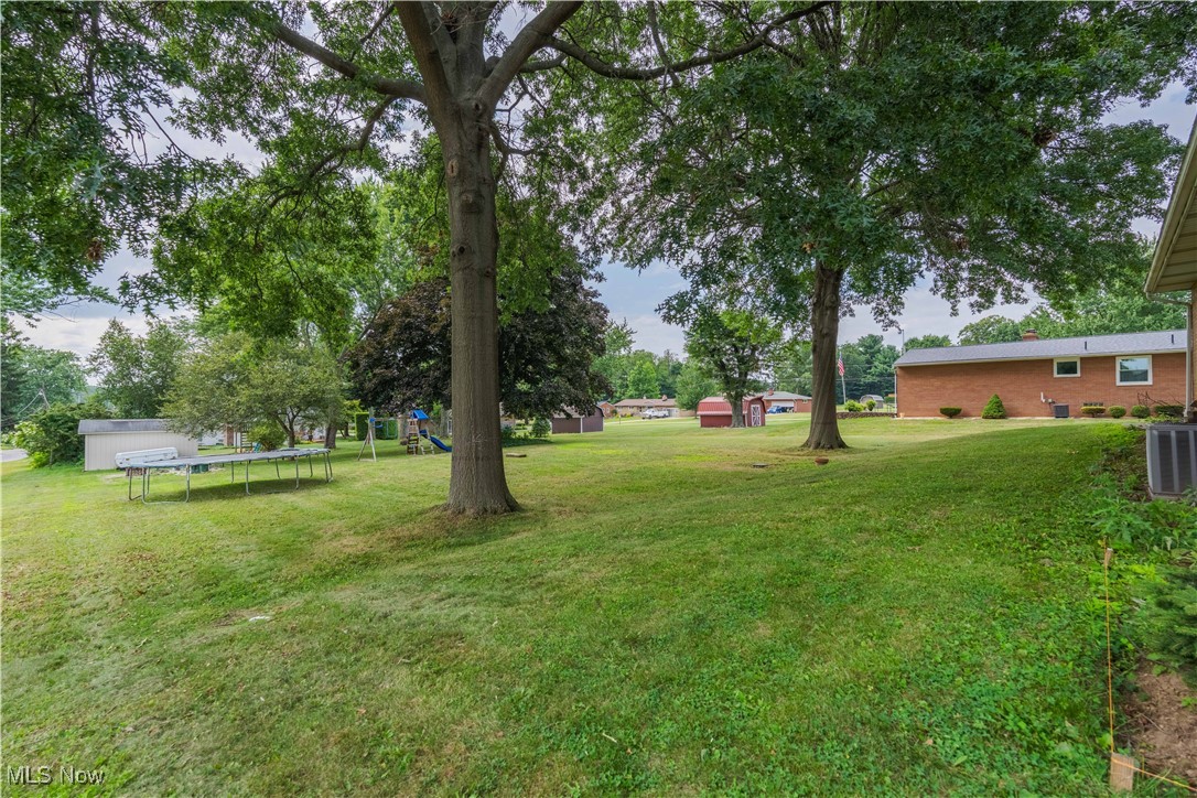 6245 Firestone Road Northeast Canton, OH 44721 - Photo 33 of 33 View of green lawn with a trampoline, a playground, and a storage unit