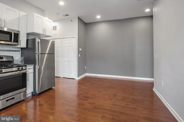 a view of kitchen with stainless steel appliances wooden floor and window