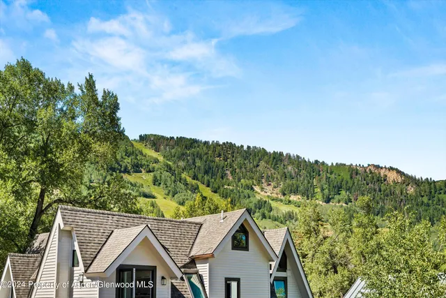 a view of a big house with a big yard plants and large trees
