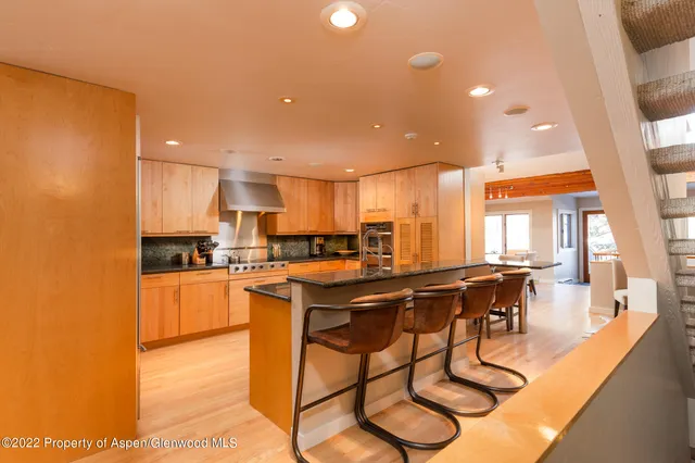 a kitchen with stainless steel appliances granite countertop a sink a stove a refrigerator cabinets and dining table