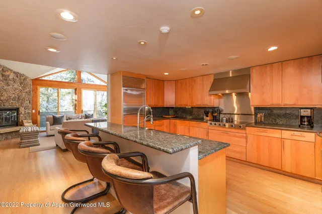 a large kitchen with kitchen island granite countertop a large counter top space a sink a stove a dining table and chairs