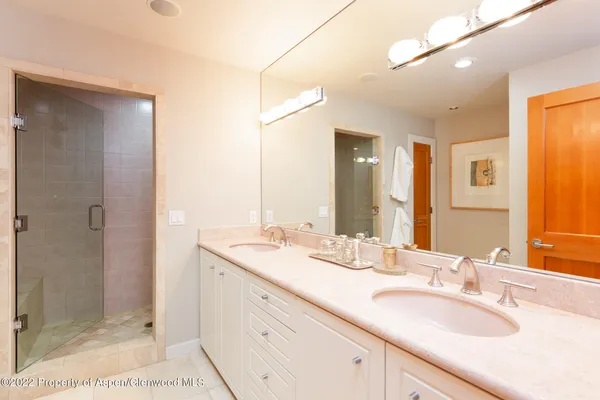 a bathroom with a granite countertop double vanity sink mirror and shower