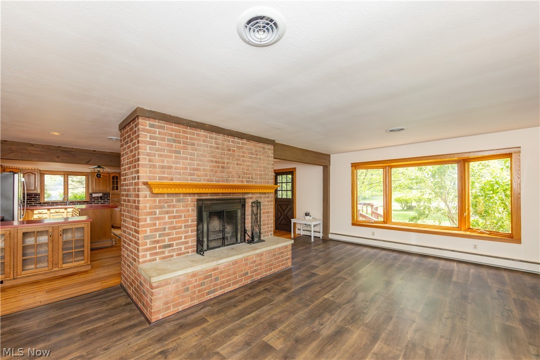 7969 Dines Road Novelty, OH 44072 - Photo 5 of 48 Spacious living area featuring a brick fireplace with a stone hearth, wood-finish flooring, and a large bay window