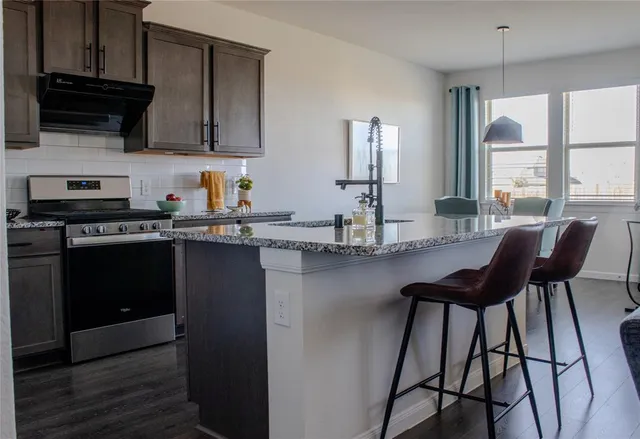 a kitchen with stainless steel appliances granite countertop sink stove top oven and cabinets