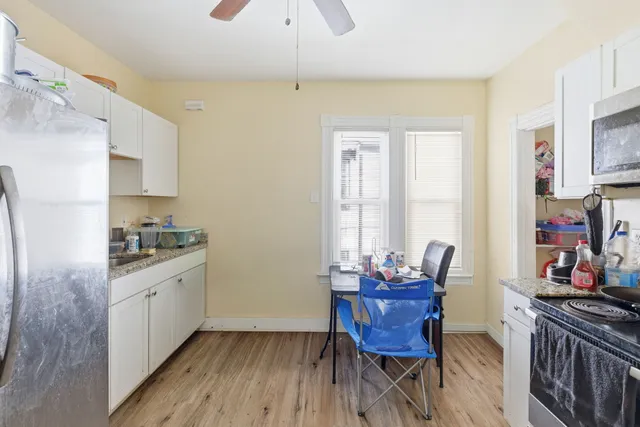 a kitchen with stainless steel appliances granite countertop a stove top oven a sink dishwasher and a dining table with wooden floor