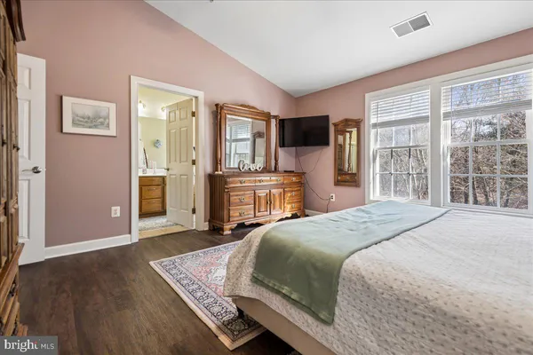 a bedroom with a large bed a flat tv screen and a dresser