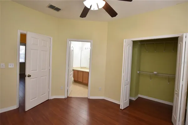 an empty room with wooden floor cabinet and windows