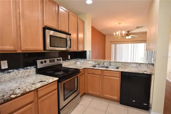 a kitchen with granite countertop a stove top oven microwave and refrigerator
