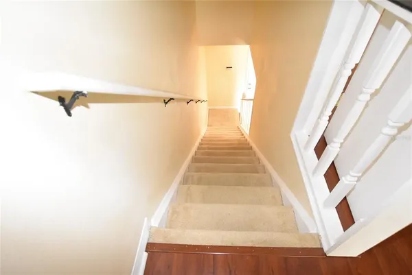 a view of a hallway with wooden floor and a bathroom