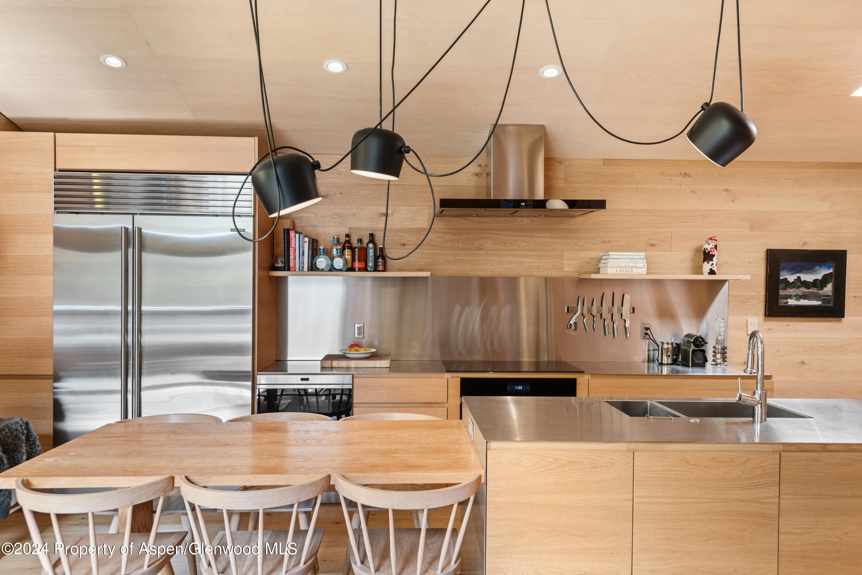 800 South Monarch Street, Unit 9 Aspen, CO 81611 - Photo 10 of 25 a kitchen with stainless steel appliances kitchen island a table chairs in it and wooden floors