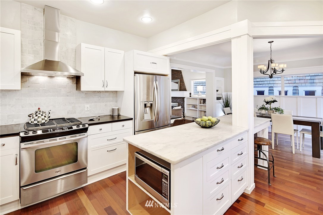 1936 47th Avenue Southwest Seattle, WA 98116 - Photo 7 of 25 a kitchen with stainless steel appliances white cabinets and wooden floor