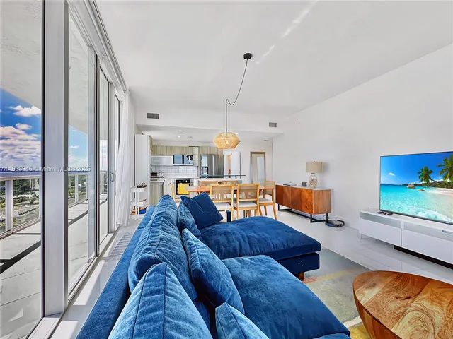 a living room with furniture a flat screen tv and a floor to ceiling window