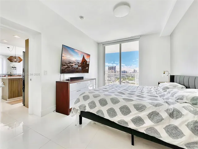 a bedroom with a bed and a flat tv screen next to a window