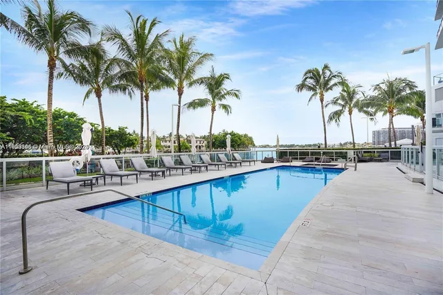 a view of swimming pool with outdoor seating and palm tree