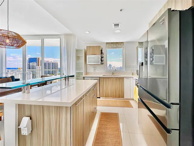a large kitchen with kitchen island a large window and stainless steel appliances