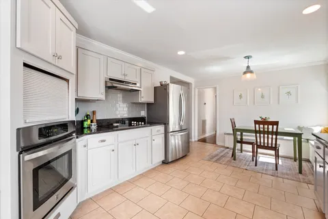 a kitchen with granite countertop a stove a sink and a refrigerator