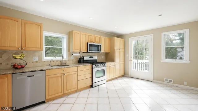 a kitchen with a stove a sink dishwasher a microwave oven and a refrigerator with wooden cabinets