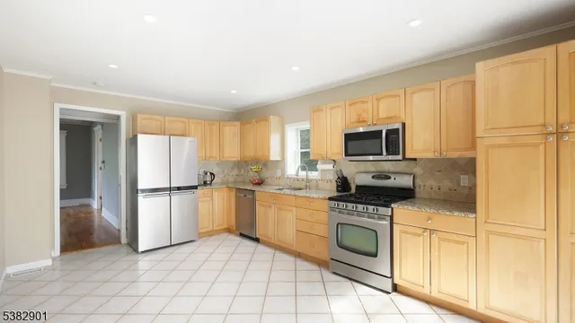 a kitchen with granite countertop a refrigerator oven a sink dishwasher and white cabinets with wooden floor
