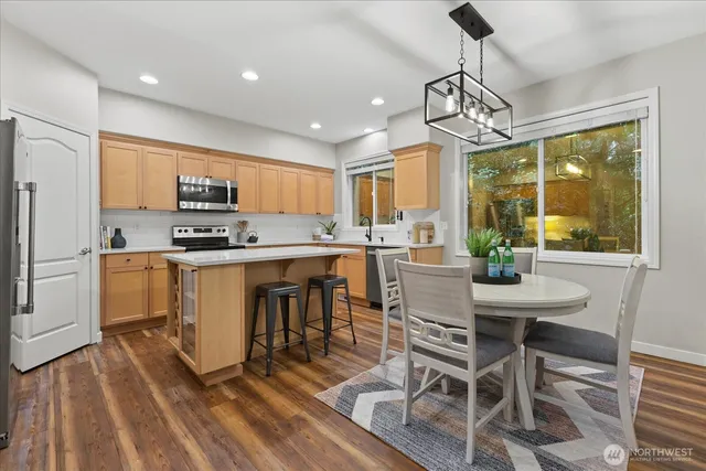 a kitchen with kitchen island granite countertop a sink a counter top space appliances and cabinets