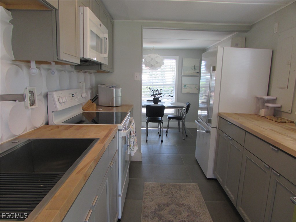 16111 Tortuga Street Bokeelia, FL 33922 - Photo 10 of 29 a kitchen with stainless steel appliances granite countertop a refrigerator a sink dishwasher a dining table and chairs with wooden floor