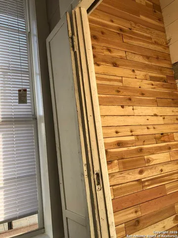 a backyard of a house with large trees and a wooden fence