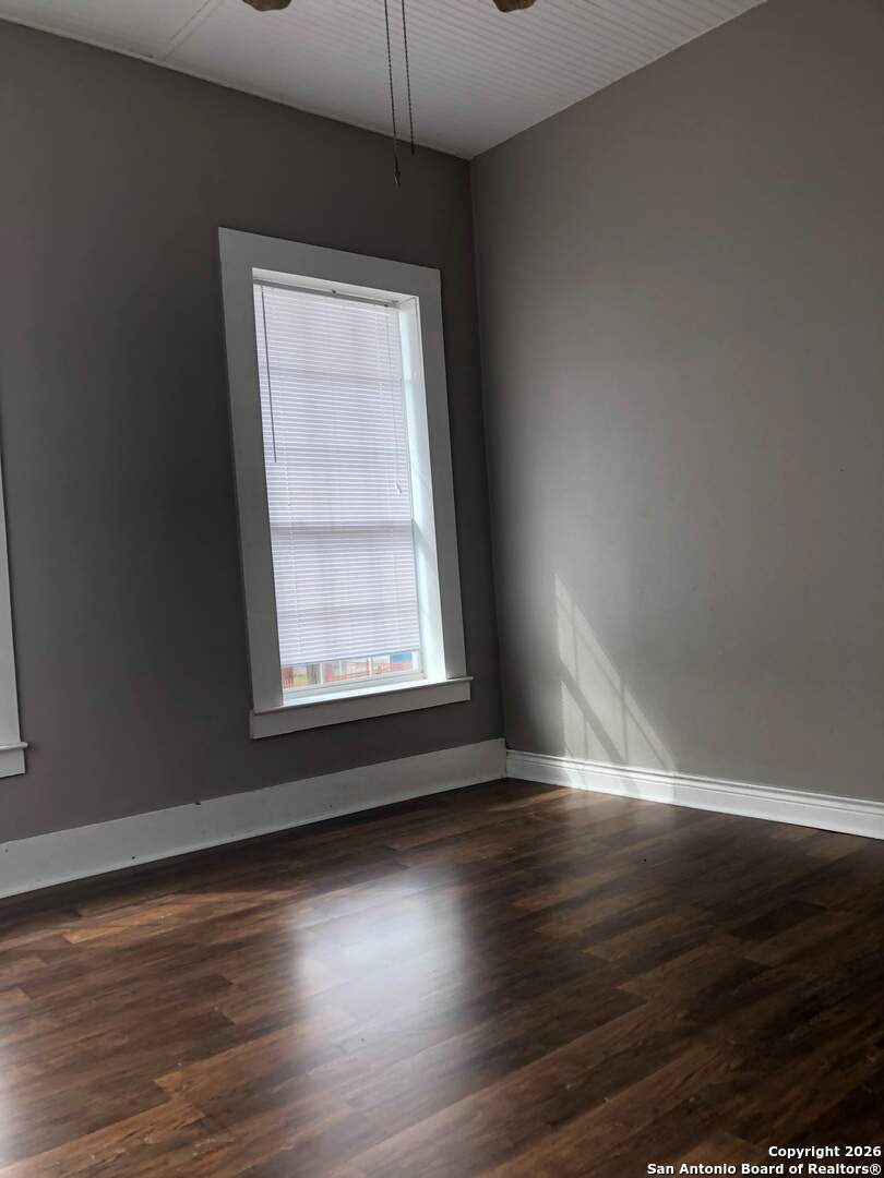 215 Rigsby Avenue San Antonio, TX 78210 - Photo 4 of 13 an empty room with wooden floor and windows
