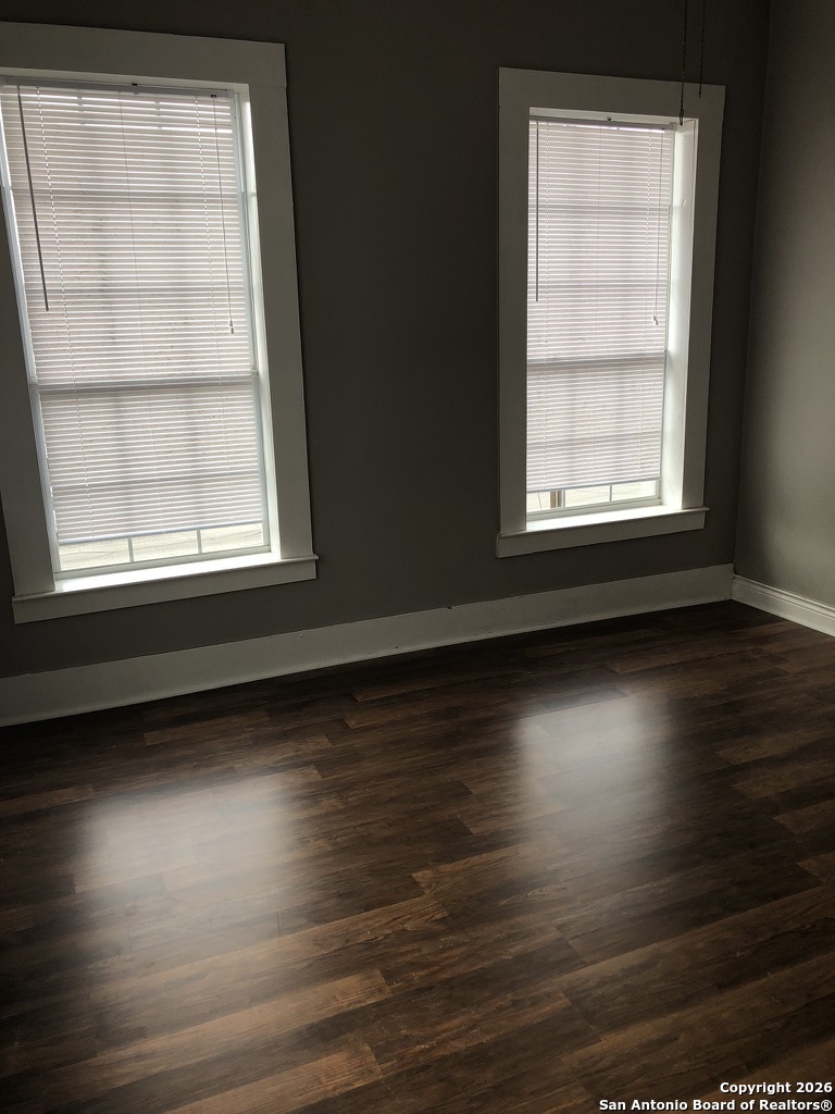 215 Rigsby Avenue San Antonio, TX 78210 - Photo 7 of 13 an empty room with wooden floor and windows