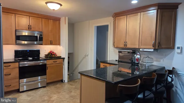 a kitchen with stainless steel appliances granite countertop a stove top oven a sink dishwasher and cabinets with wooden floor