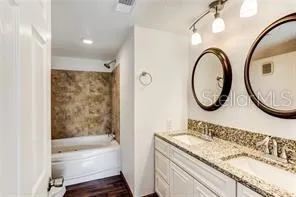 a bathroom with a granite countertop sink mirror toilet and bathtub