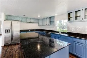a kitchen with stainless steel appliances granite countertop a sink a stove and a refrigerator