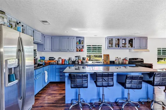 a kitchen with stainless steel appliances granite countertop a stove top oven a refrigerator a sink and dishwasher with wooden floor