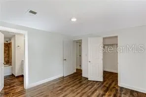 a view of an empty room with wooden floor and closet