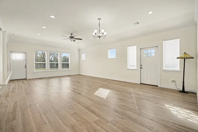 an empty room with wooden floor cabinet and windows