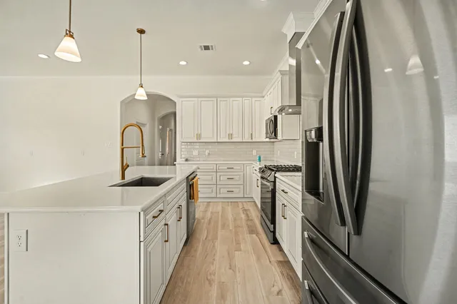 a kitchen with stainless steel appliances a refrigerator sink and white cabinets