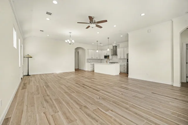 a view of a kitchen with kitchen island a sink wooden floor and stainless steel appliances