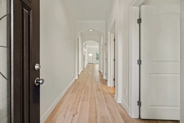 a view of a hallway with wooden floor and a bathroom