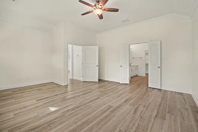 an empty room with wooden floor ceiling fan and windows
