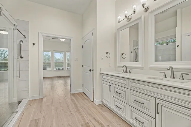 a spacious bathroom with a granite countertop sink a mirror a vanity and a shower