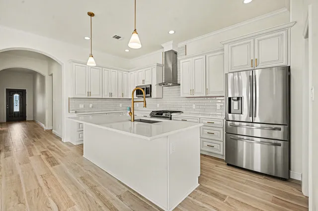 a white kitchen with wooden floor and stainless steel appliances