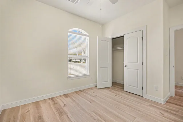 an empty room with wooden floor and windows