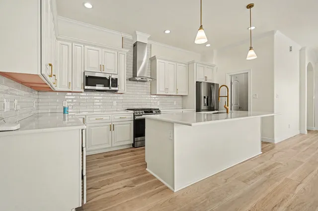 a kitchen with kitchen island white cabinets and stainless steel appliances